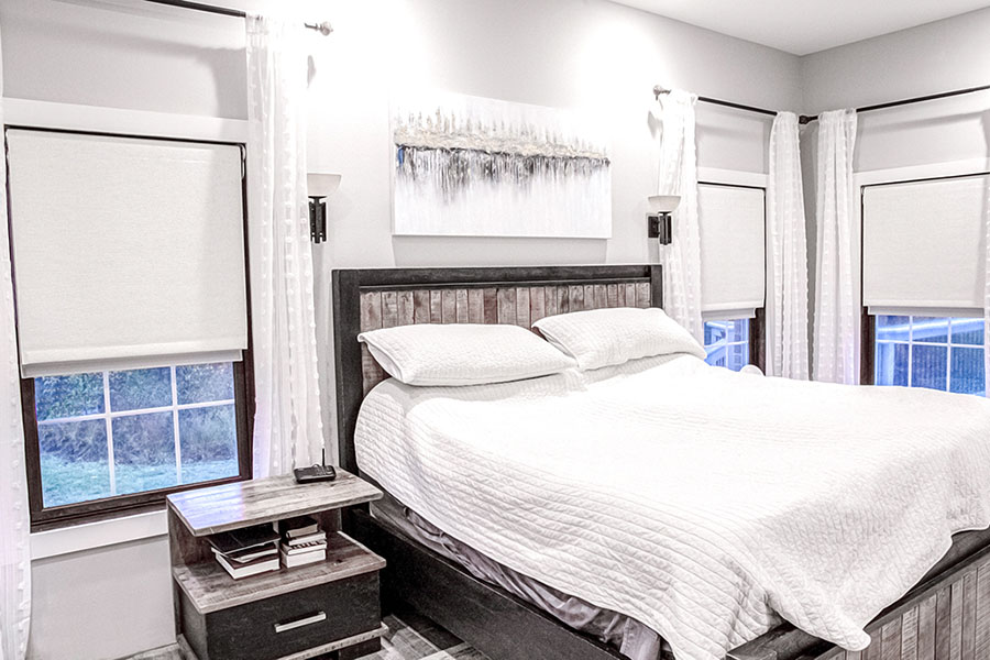 White Roman shades on windows in a farmhouse-style bedroom