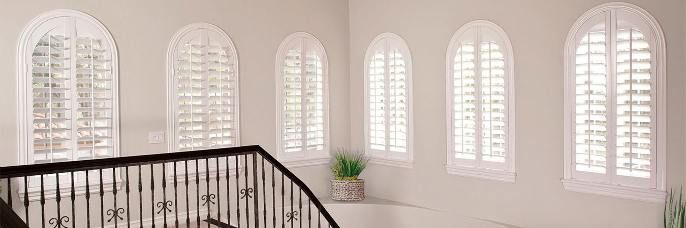 Six arched windows with white Polywood shutters in an elegant stairwell
