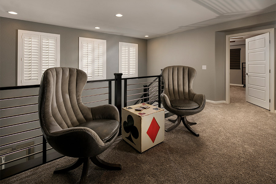 A white window treatment on a darker wall can do wonders for your Raleigh home. two chairs and a small dice-themed table in front of a stairwell with shuttered covered small windows