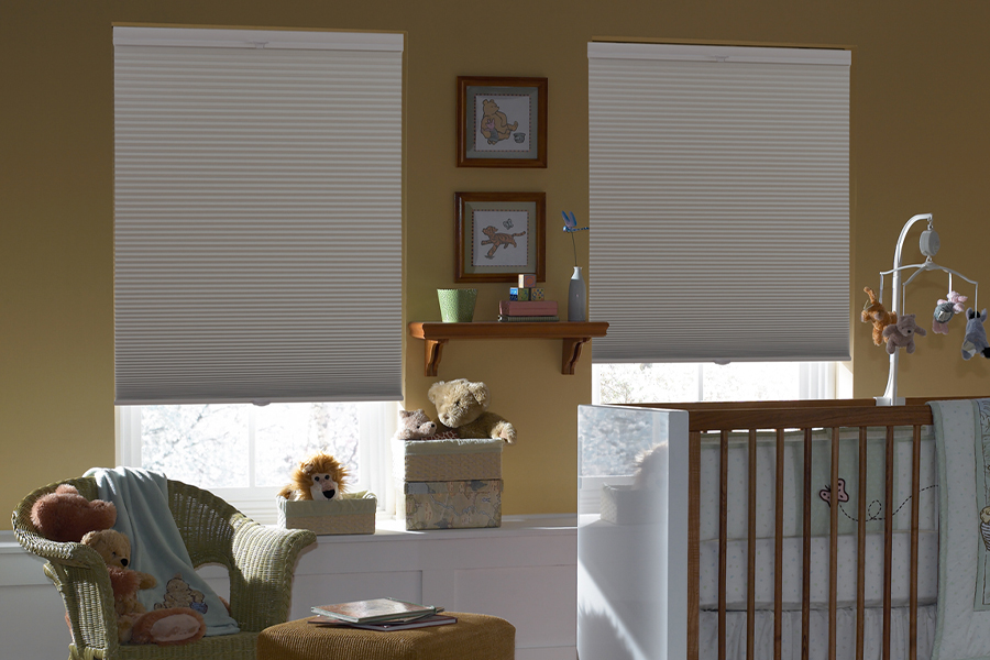 Blackout gray cellular shades in two windows. Displayed inside a baby room.