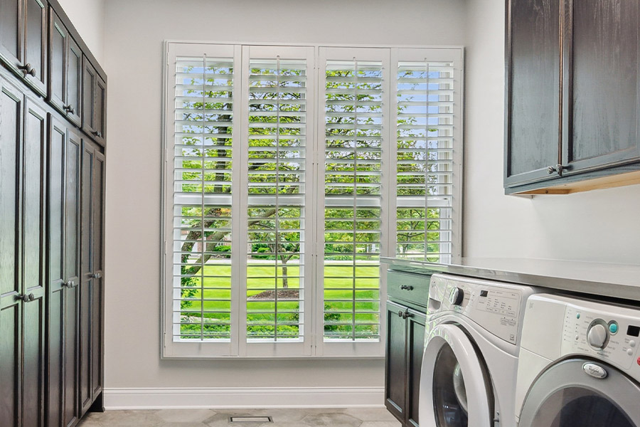 Find the perfect level of natural light for your Raleigh laundry room with interior shutters. White Polywood shutters letting light through a laundry room window