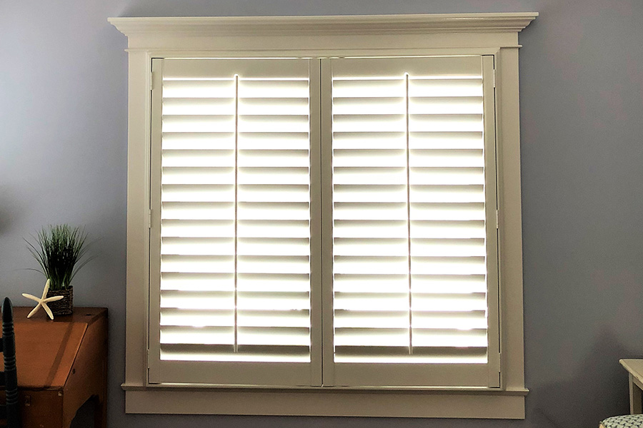 Choose elegant Polywood shutters for your dormer window. Dormer window with white Polywood shutters. Inside an attic room.