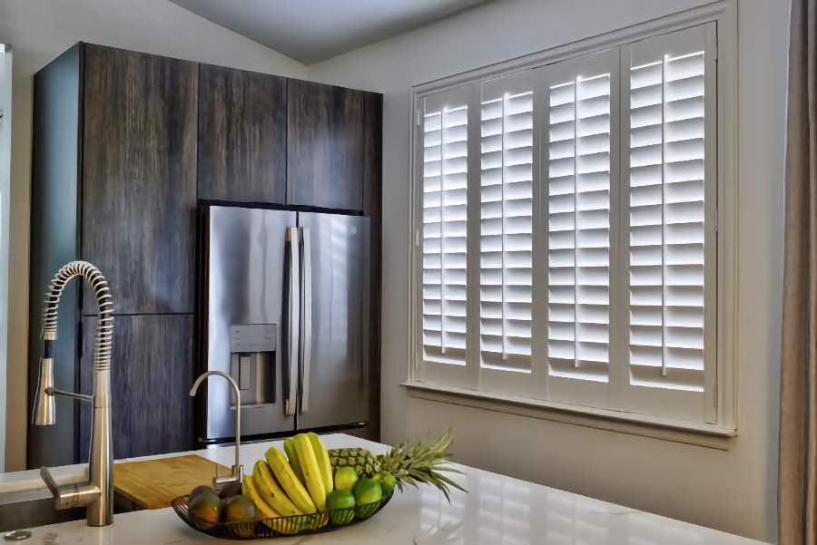 Homeowners use indoor window shutters in Raleigh when they want attractive and functional window treatments. Polywood shutters on a large kitchen window