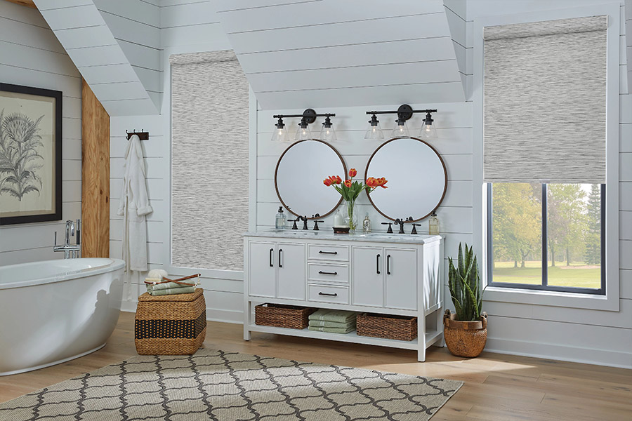 Slim-profile roller shades easily fit shallow windows in your Raleigh home. Gray patterned roller shades on bathroom windows