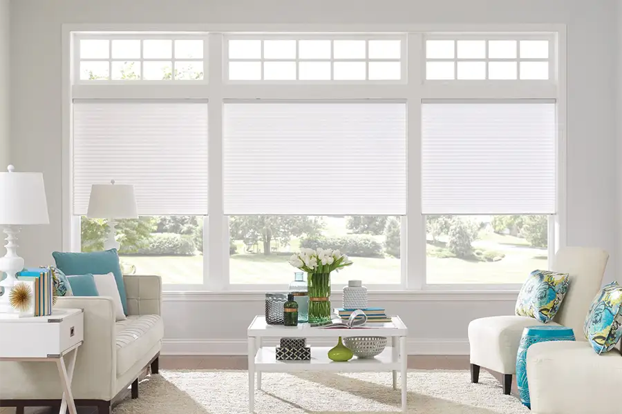 Insulating cellular shades can help keep cold air and hot UV rays from entering your Raleigh home. White cellular shades on windows in a white living room