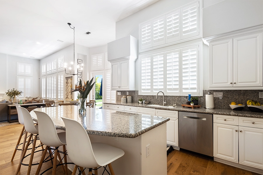 Indoor shutters are popular solid window treatments suitable for any window in your Raleigh house. White Polywood shutters on kitchen windows